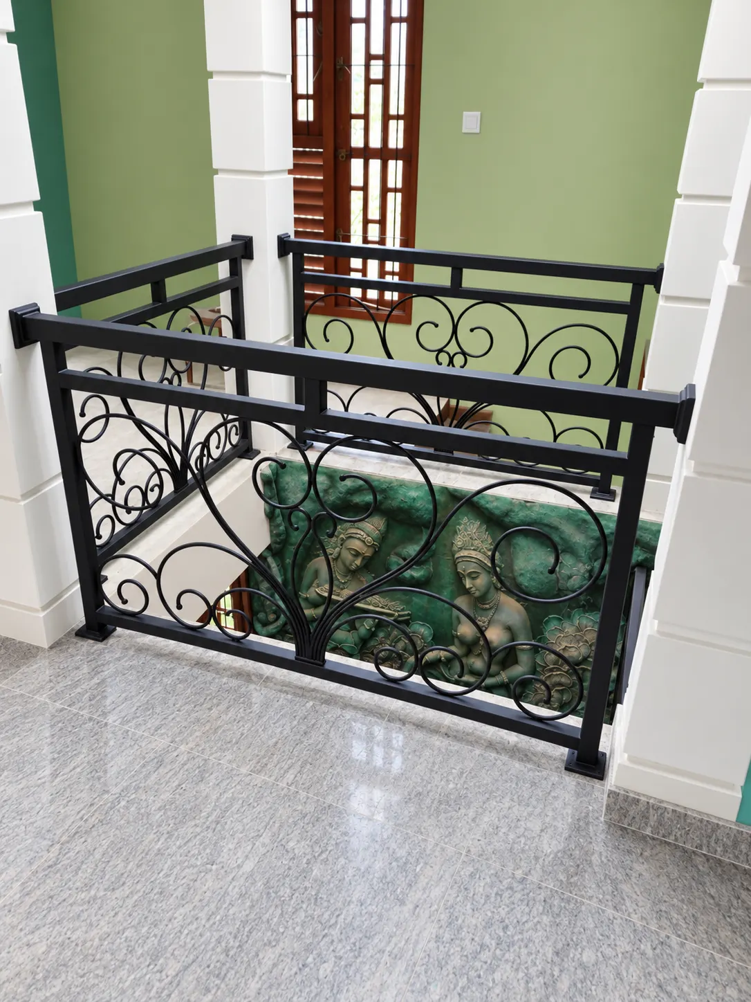Decorative scroll railing detail against a green wall