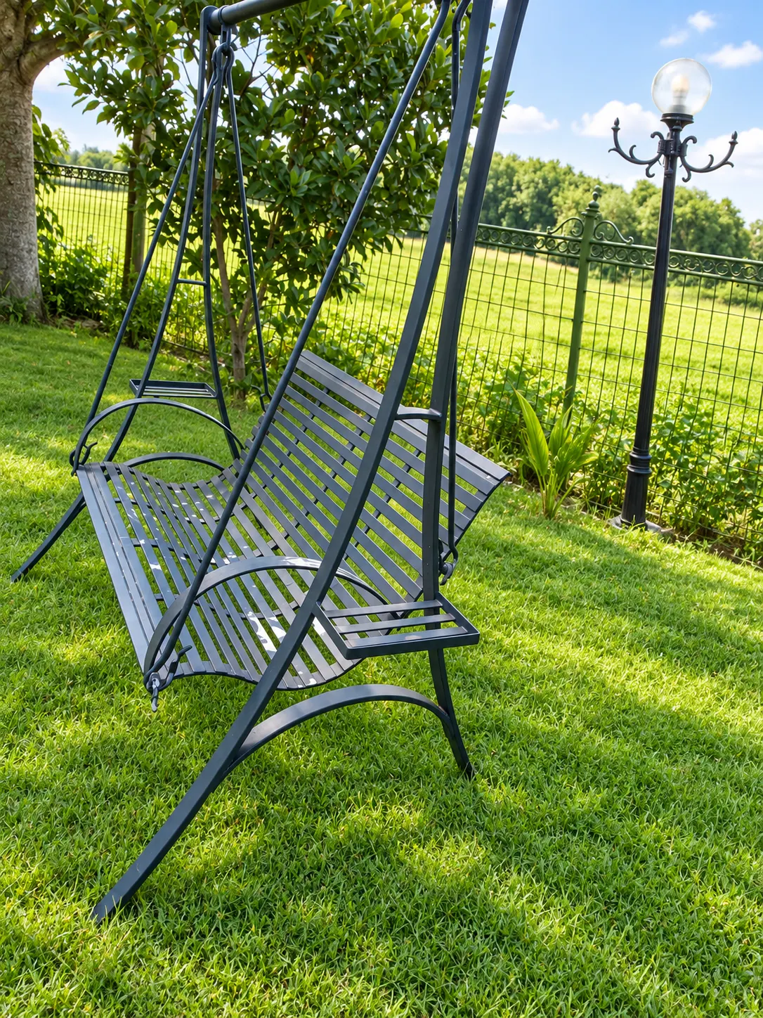 Finished black steel garden swing bench on a lawn